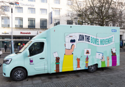 The picture is of a pale bule van with a white banner saying ' JOIN THE BOWLE MOVEMENT'.